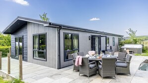 A modern building with large windows and a patio area with outdoor furniture.