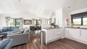 A modern kitchen with white cabinets, a dining area with a table and chairs, and a living room with a sofa and a coffee table.