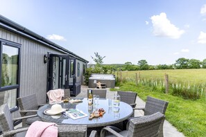 Enjoy al fresco dining in a serene outdoor setting with a round table and wicker chairs.