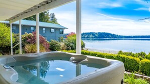 Ein Whirlpool mit freiem Blick auf einen See und ein Haus im Hintergrund.