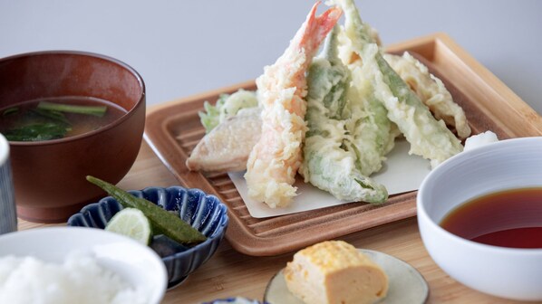 Una comida tradicional japonesa con un tazón de sopa, un plato de tempura y un tazón de salsa de soja.