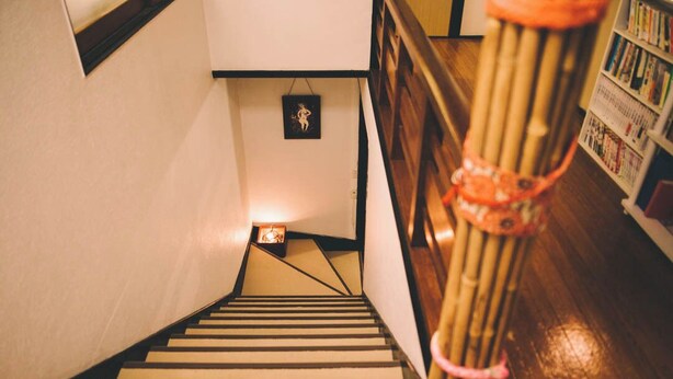 Una escalera de madera con barandilla que conduce a una plataforma con un cuadro enmarcado.