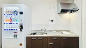 Una cuina americana equipada amb una màquina de cafè integrada, un rentapelats i una campana extractora d'acer inoxidable.