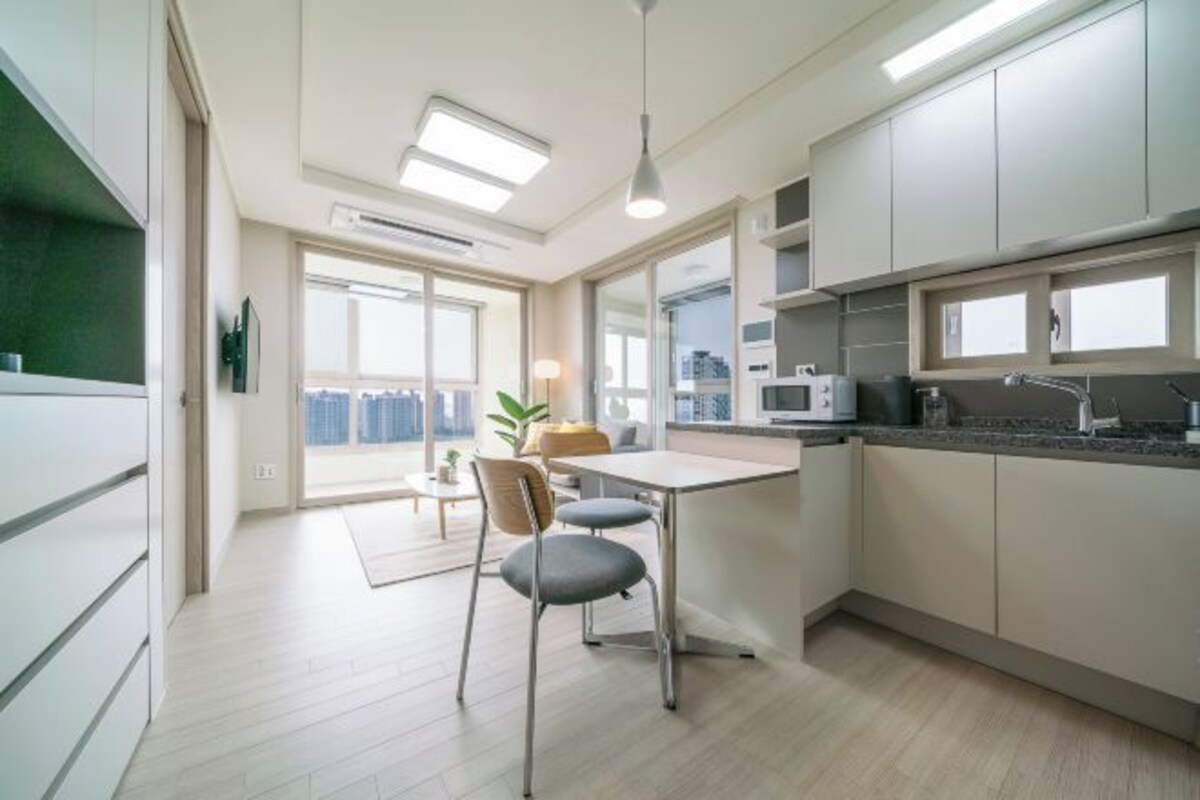 A modern kitchen with a dining area, large windows, and a view of the city.