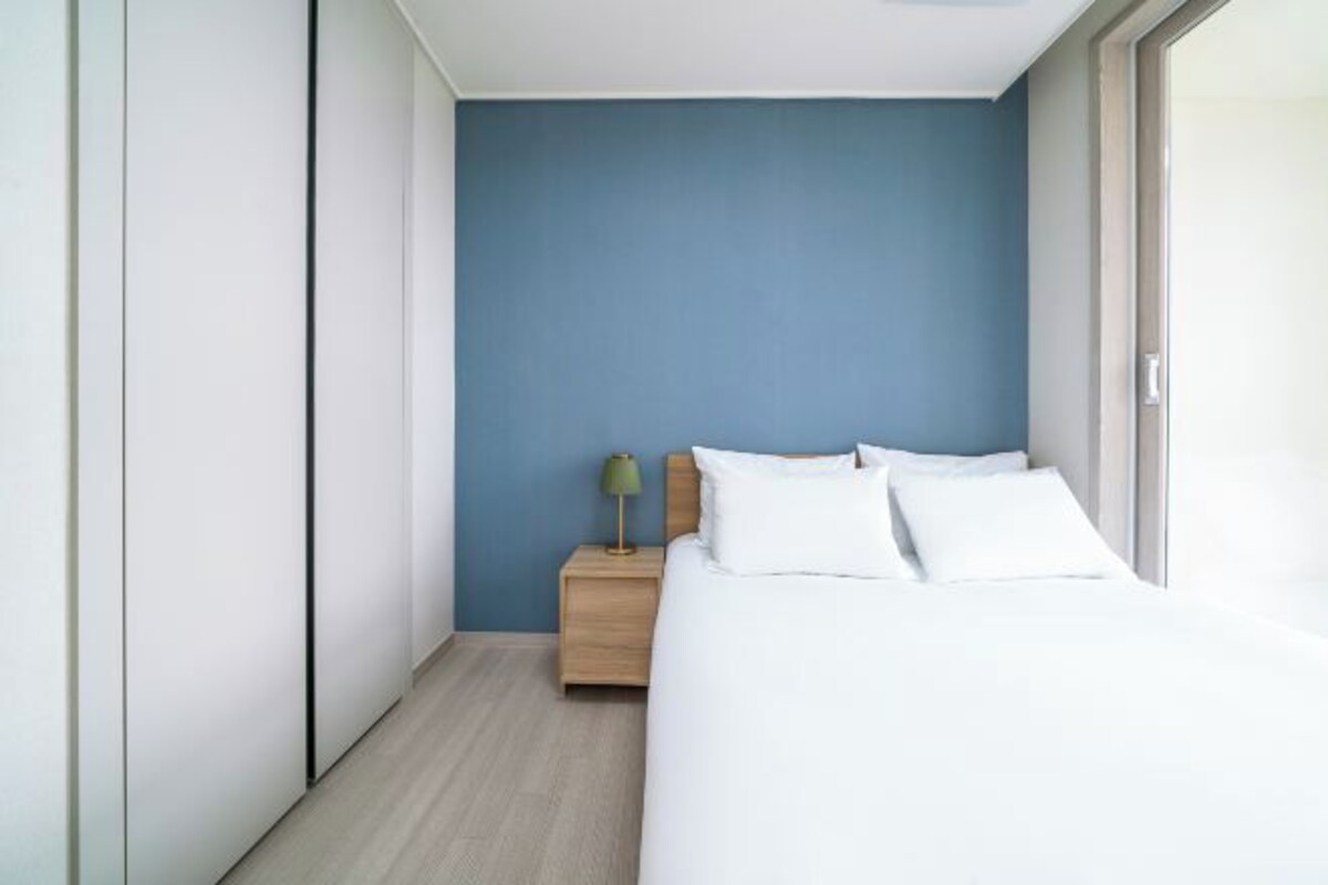 A modern bedroom with a bed, a nightstand, and a lamp.