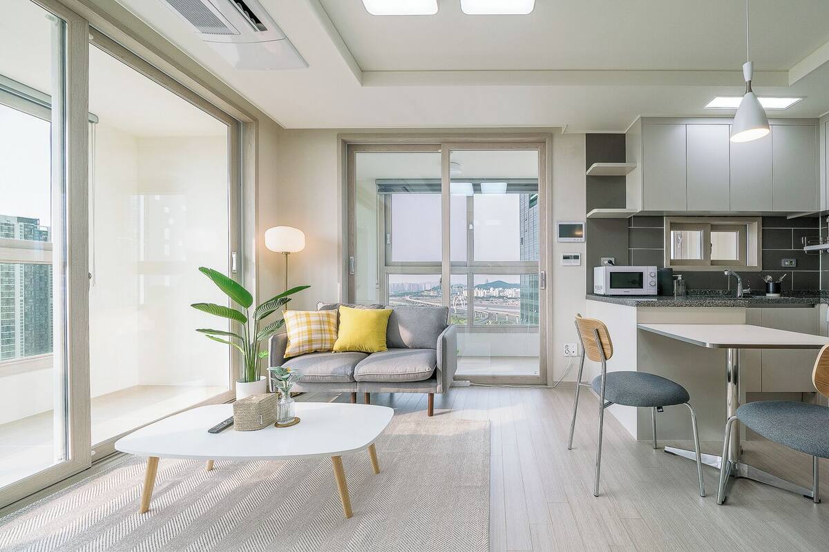Un apartamento moderno con comedor, cocina y un amplio ventanal con vistas a la ciudad.