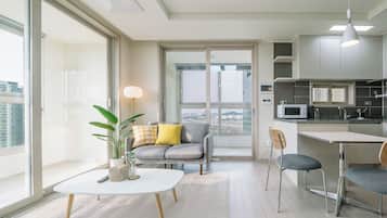 Un appartement moderne comprenant un coin repas, une cuisine et une grande fenêtre offrant une vue sur la ville.