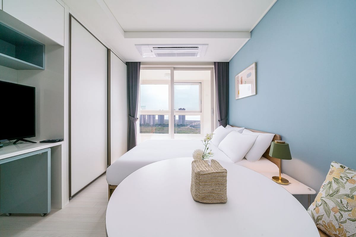 Una habitación de hotel con cama, televisión, escritorio y vista a la ciudad.