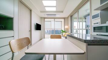 A modern kitchen with a dining area, built-in appliances, and a large window offering a city view.