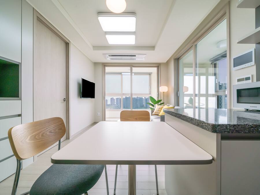 A modern kitchen with a dining area, built-in appliances, and a large window offering a city view.