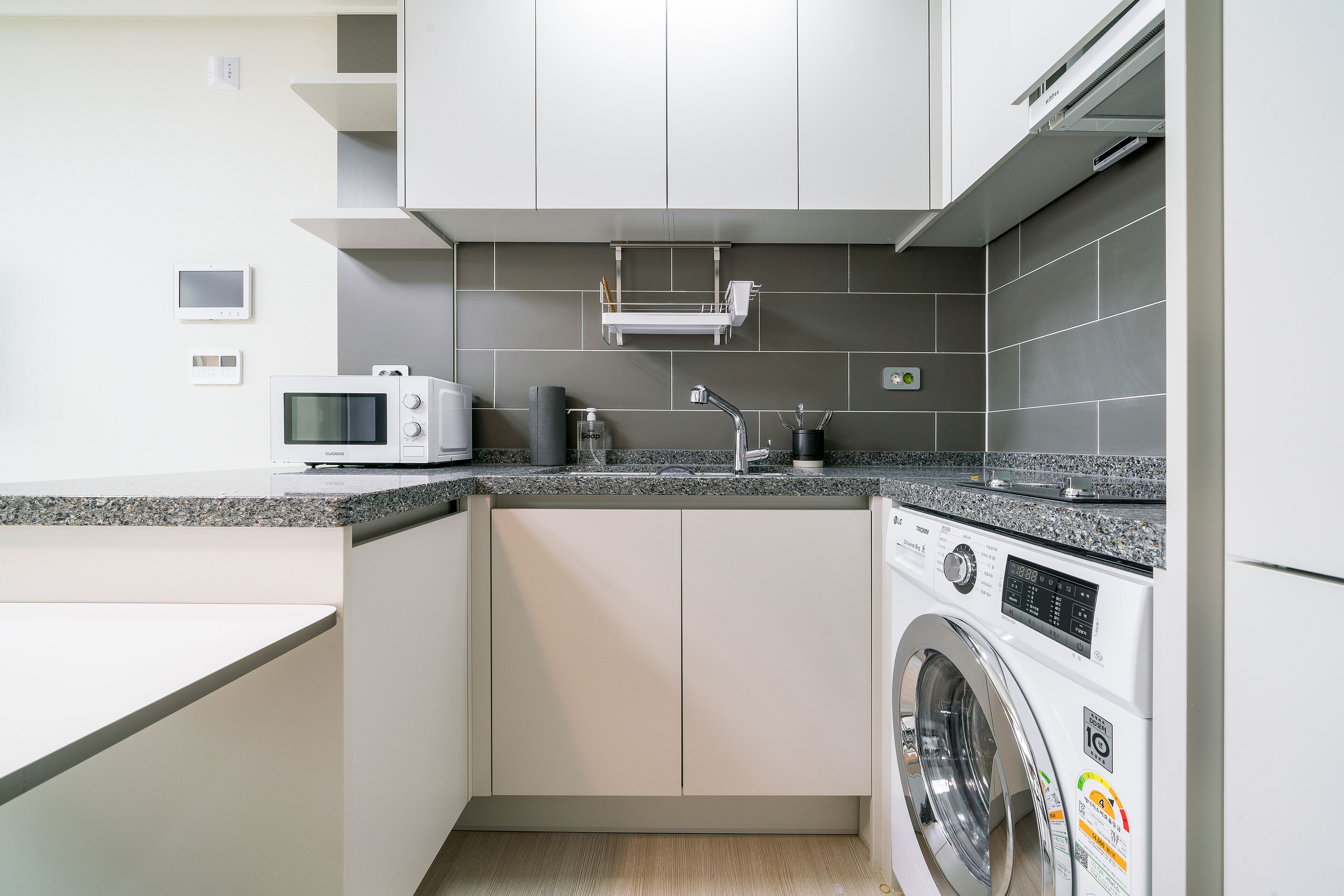 A compact kitchen with a washing machine, microwave, and a small countertop.
