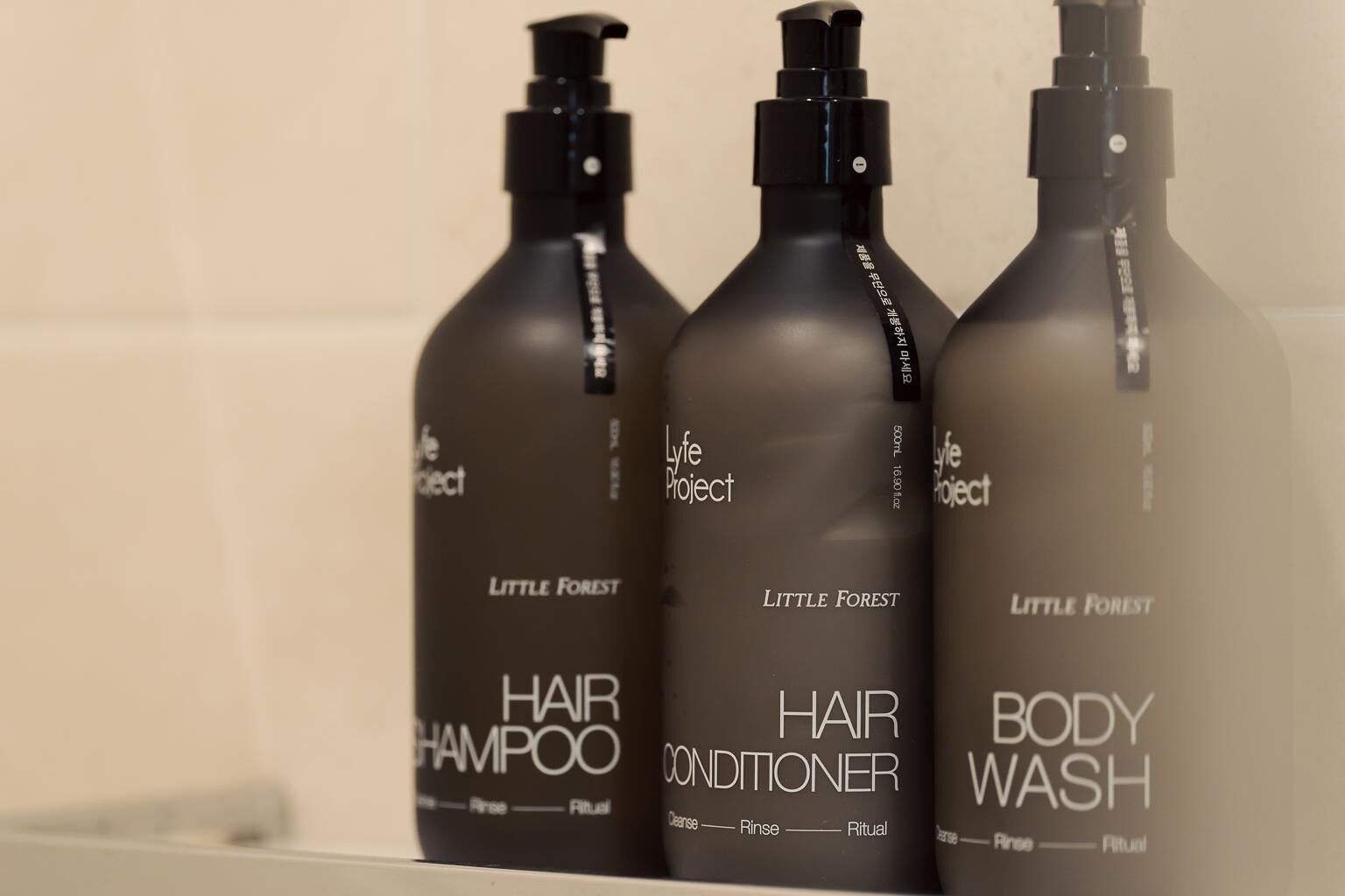 Trois bouteilles de produits capillaires de la marque Little Forest sont posées sur une étagère.