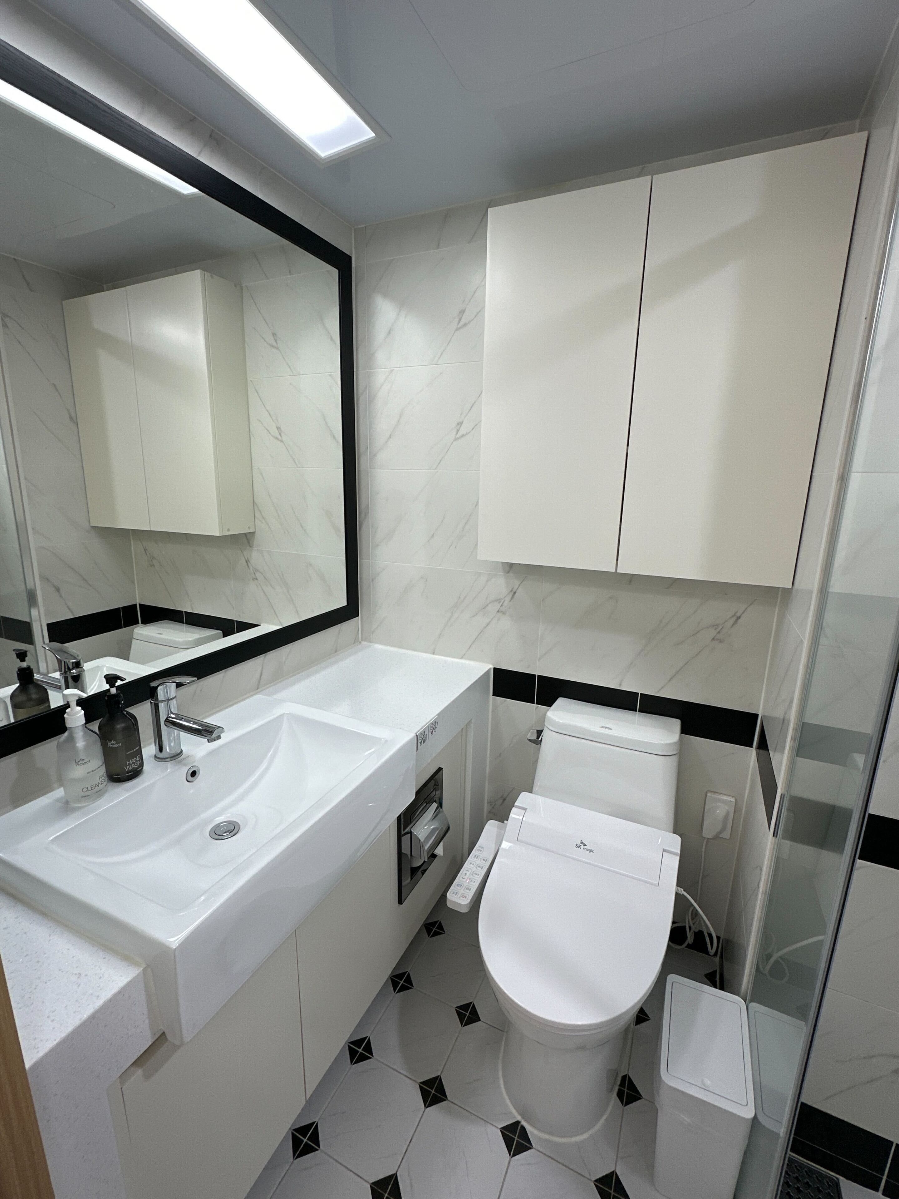 Een moderne badkamer met een wit wastafelmeubel, spiegel en toilet.