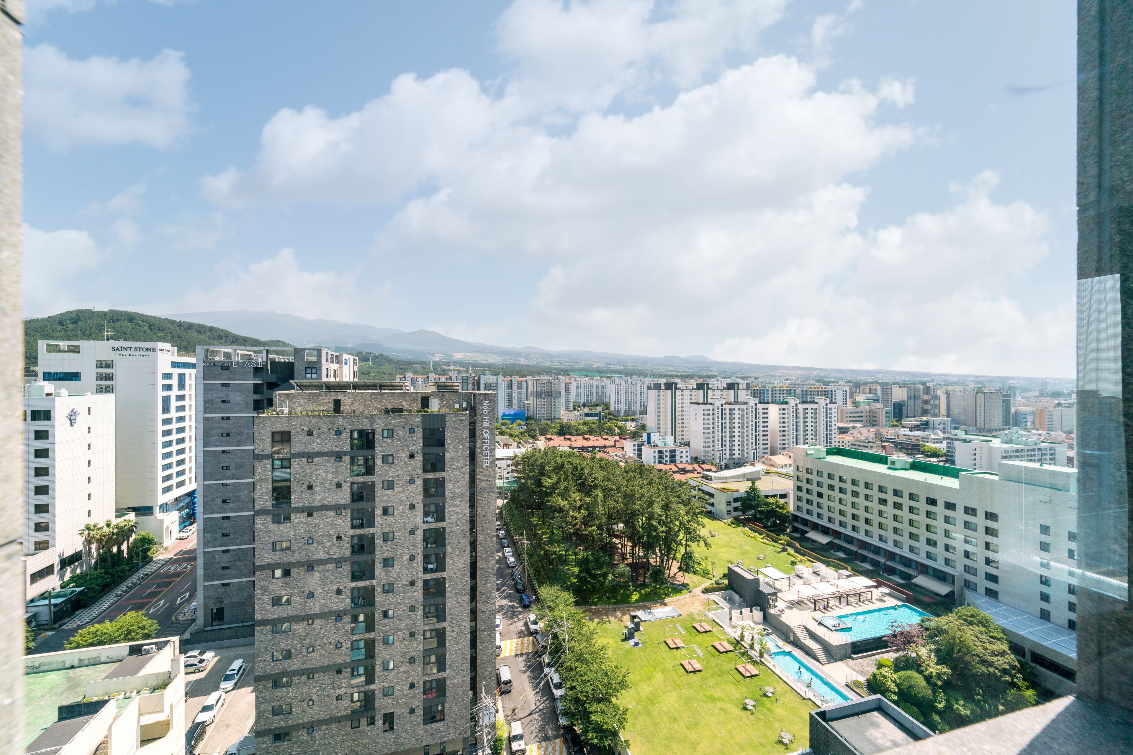 A high-rise building with a rooftop pool and a green lawn.