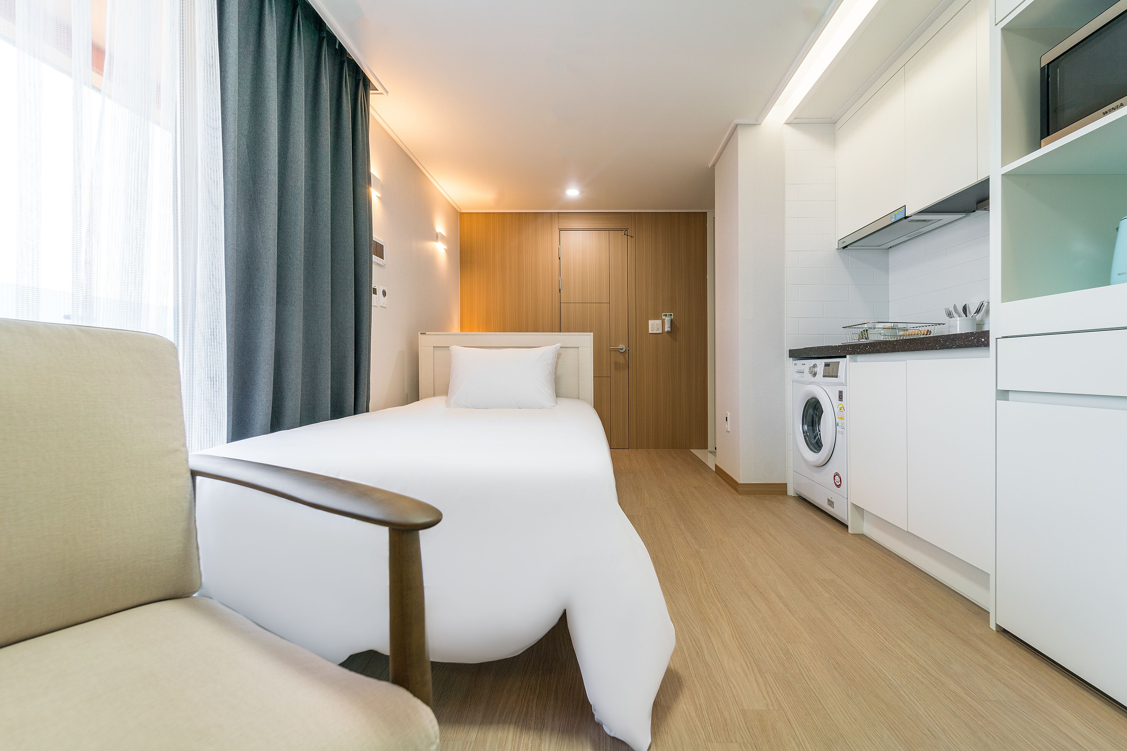 Une chambre d’hôtel équipée d’un lit, d’une chaise, d’un lave-linge et d’une kitchenette.