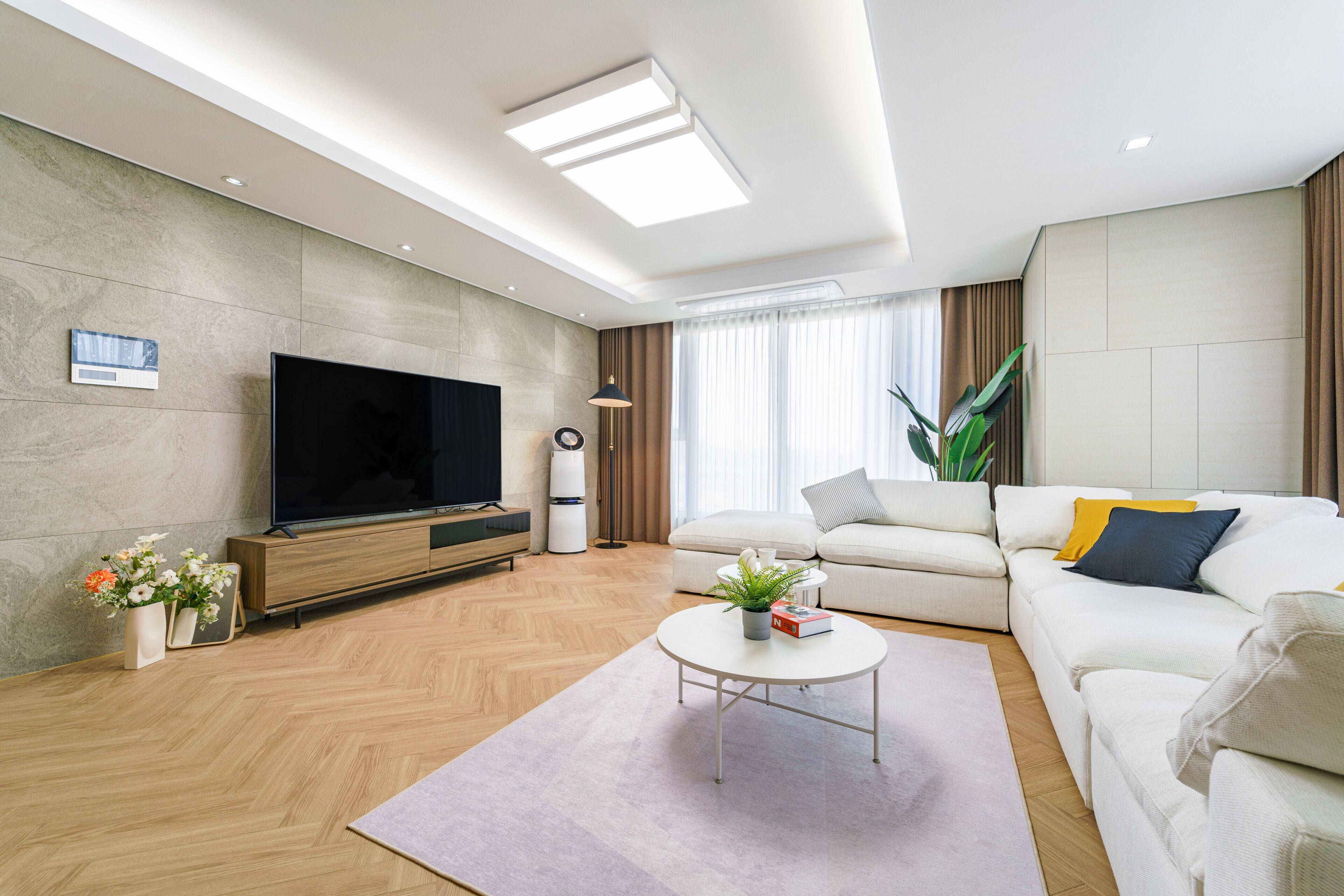 Una sala de estar moderna con una televisión de pantalla plana, un sofá, una mesa de centro y una planta en maceta.