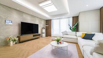 Una sala de estar moderna con una televisión de pantalla plana, un sofá, una mesa de centro y una planta en maceta.