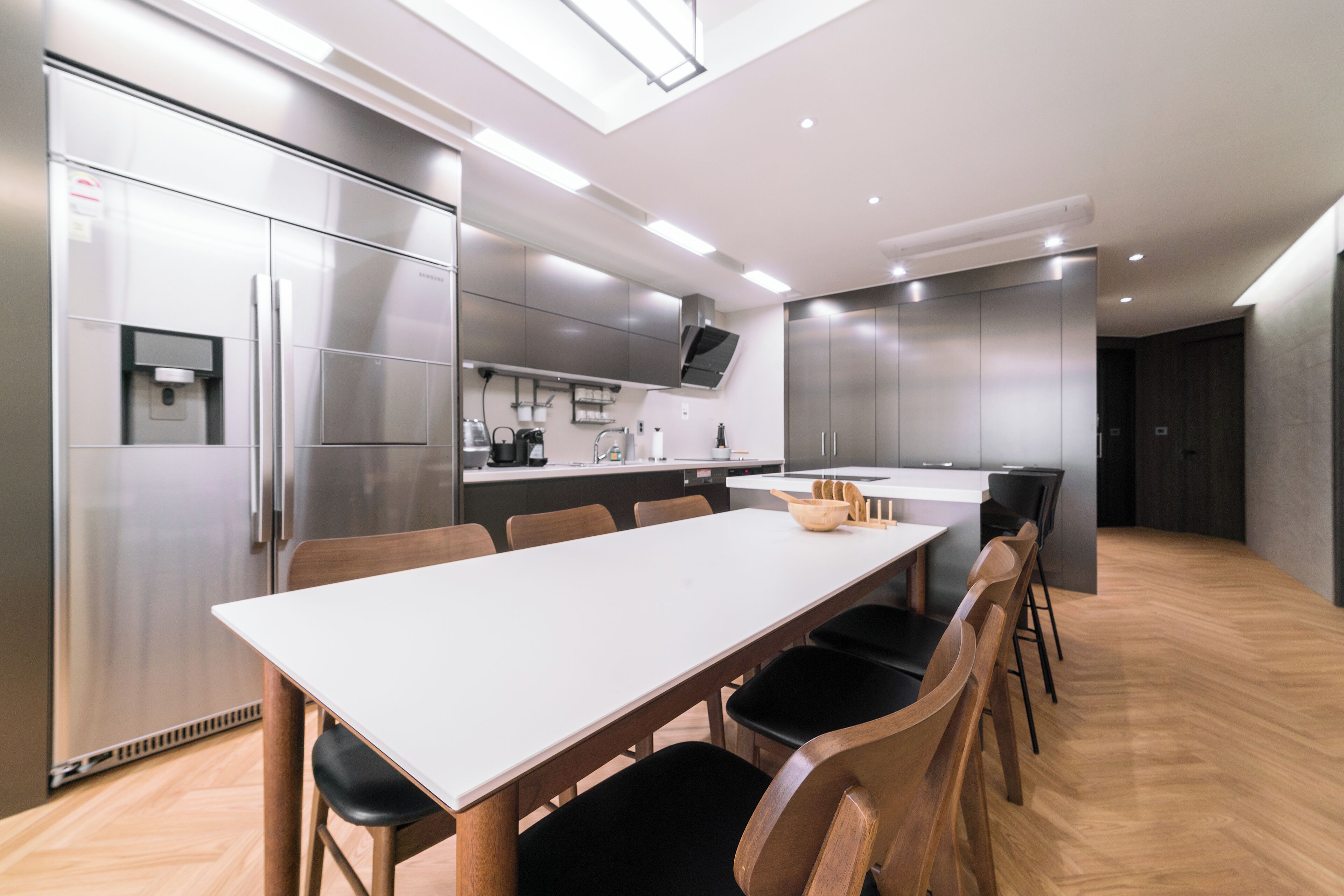 A modern kitchen with a white table and black chairs, stainless steel appliances, and a built-in oven.