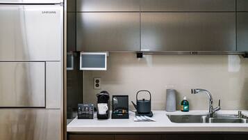 A modern kitchen with stainless steel appliances, a coffee maker, a kettle, and a sink.