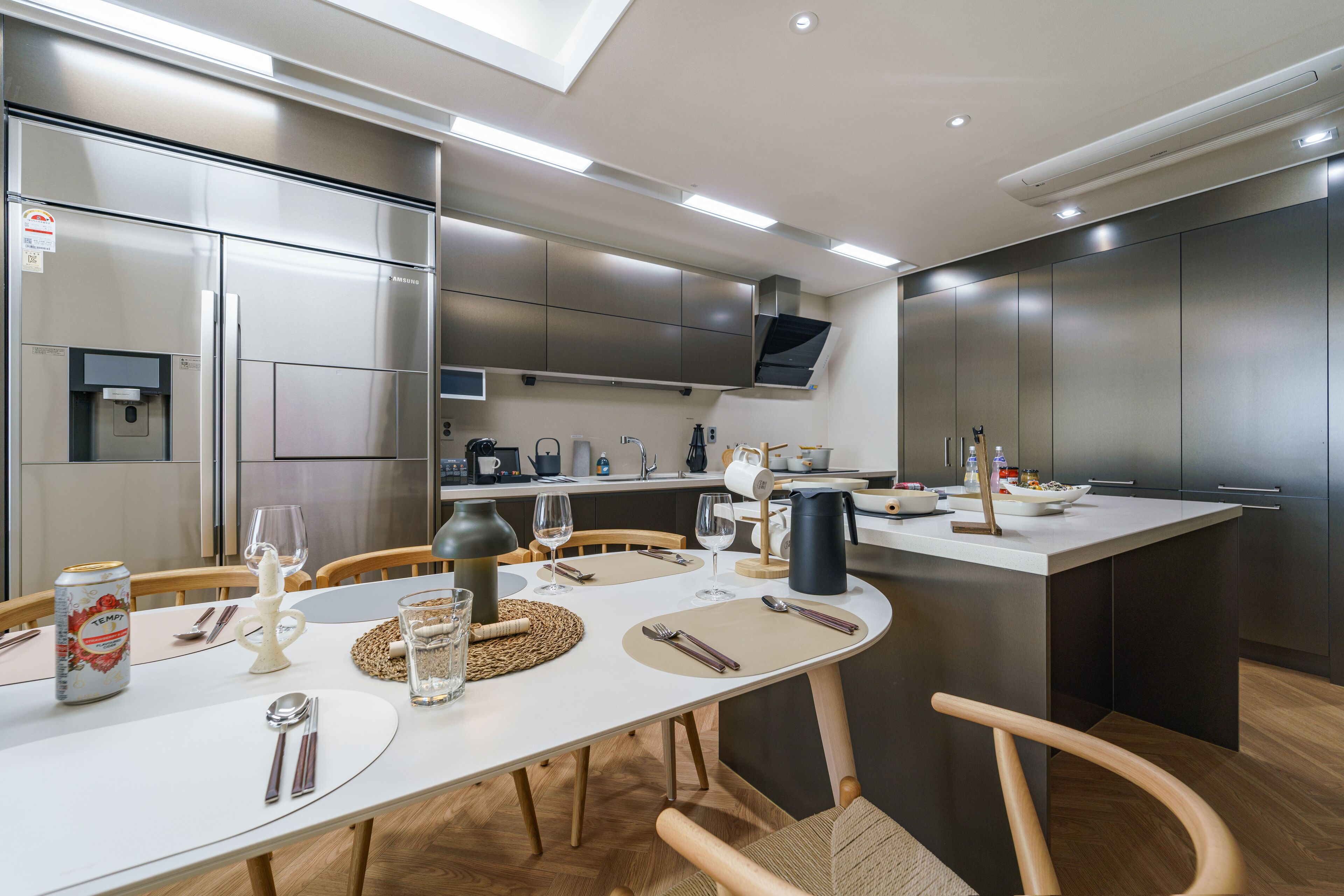 A modern kitchen with stainless steel appliances, a dining area with a white table, and wooden chairs.