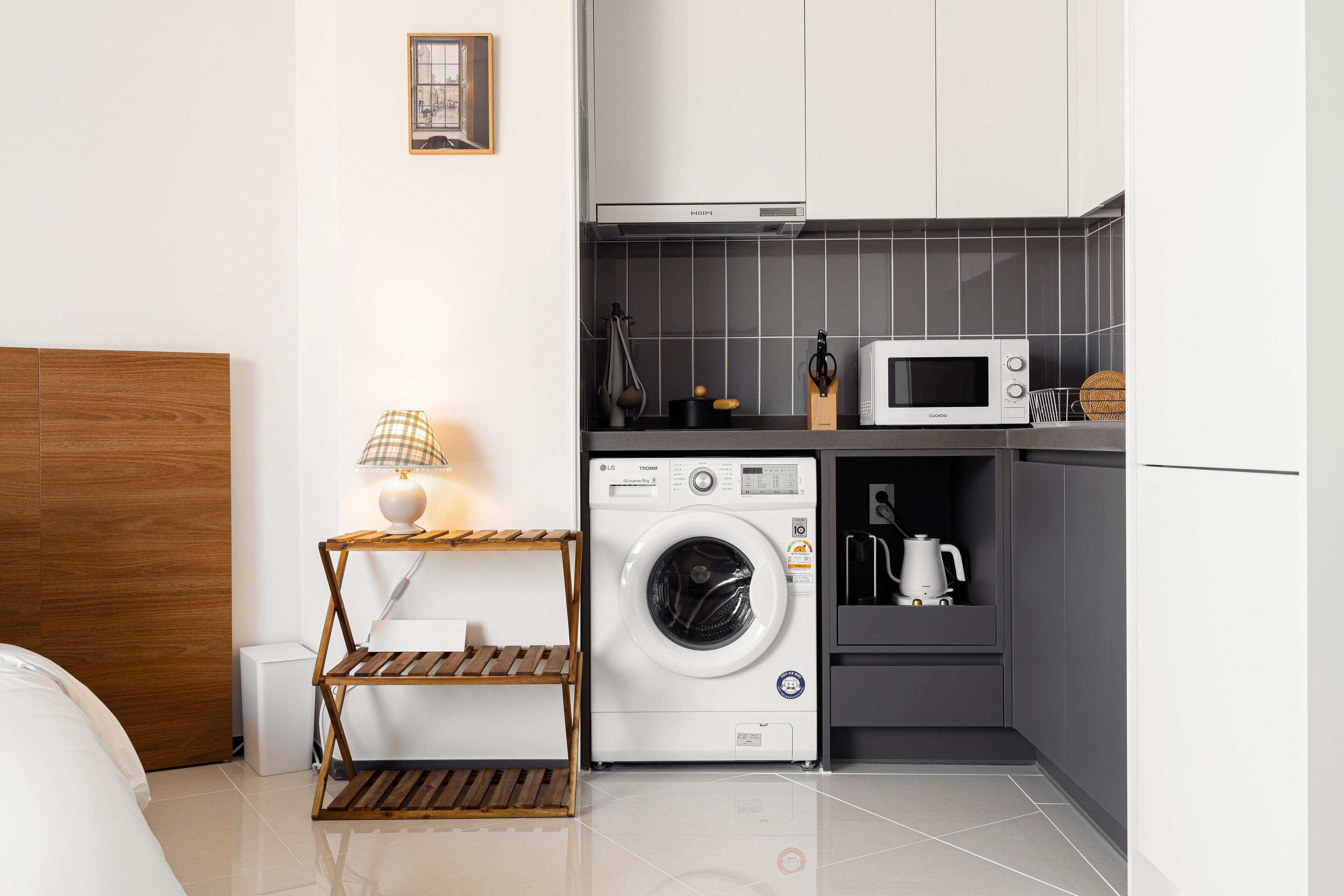 A compact hotel room with a washing machine, microwave, and a small kitchenette.