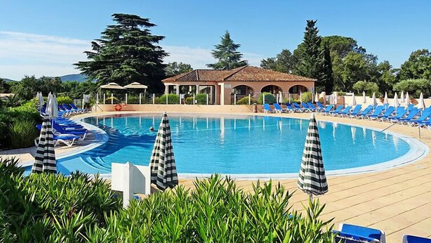Un espace piscine agrémenté de chaises longues bleues, d’un pavillon abrité et d’une végétation luxuriante.
