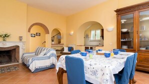 Un coin repas avec une table dressée pour quatre personnes, des chaises bleues et un buffet en bois doté de portes en verre.