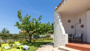 A covered outdoor area with a stone wall, a tree, and two yellow lounge chairs. - Vacation home Moru by Interhome (Deltebre)