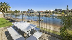 A fenced outdoor area with picnic tables and a body of water.