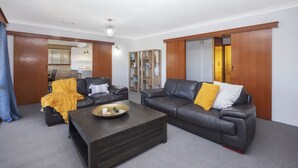 A living room with two leather sofas, a coffee table, and a bookshelf.