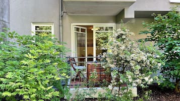 Ein Wohngebäude mit Balkon, einer Holzterrasse und einem Gartenbereich mit verschiedenen Pflanzen.