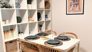 A dining area with a white table, wicker chairs, and a white shelving unit with various items. - JUPAS° | Red Rock Home - Balcony & Parking lot (Trier)