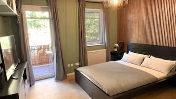 Ein Schlafzimmer mit einem Bett, einem Schreibtisch, einem Stuhl, einem Fenster mit Vorhängen und einer Pendelleuchte.
