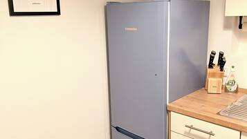 Eine Küche mit einem blauen Liebherr-Kühlschrank, einer Holzarbeitsplatte, einem Spülbecken und einem Bilderrahmen mit einem Lama-Bild.