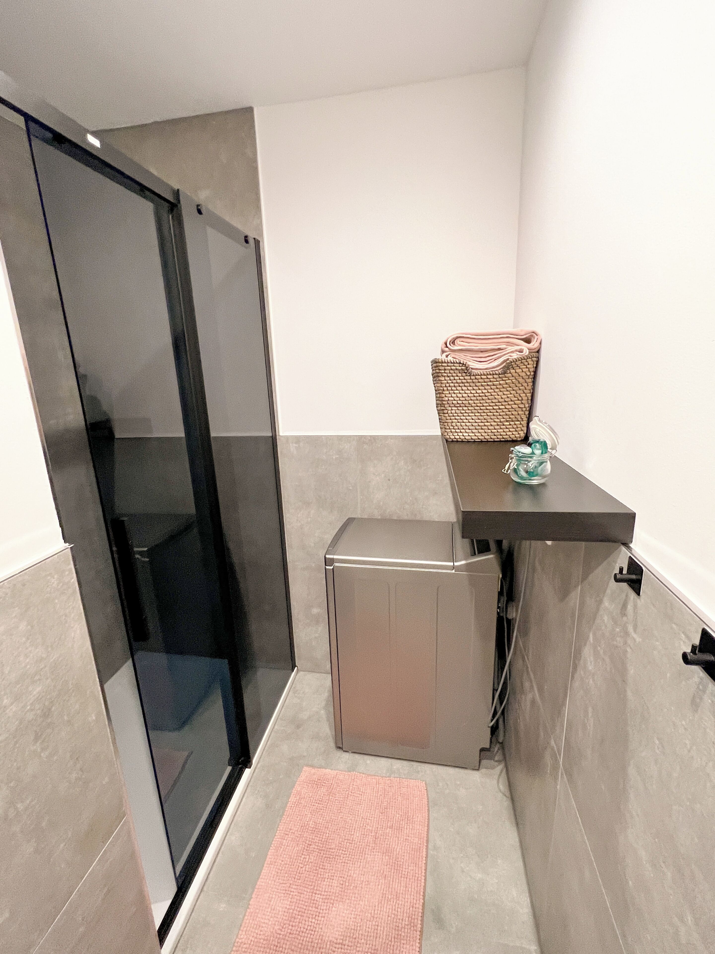 A compact bathroom with a glass shower door, a small sink, and a towel rack.