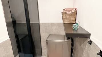 A compact bathroom with a glass shower door, a small sink, and a towel rack.