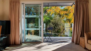 A room with a sliding glass door leading to a balcony with autumn foliage.