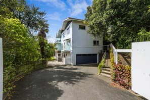 A residential building with a garage, a covered porch, and a staircase leading to the entrance. - Kimberley House - 6-bedroom home in a fantastic Nelson waterfront location. (Nelson)