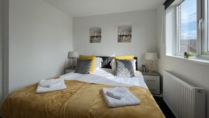 Habitación de hotel con cama, dos mesitas de noche, una ventana y obras de arte en la pared.