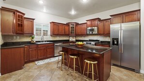 Una cocina moderna con armarios de madera, electrodomésticos de acero inoxidable y una isla central con taburetes.