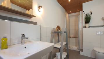 Une salle de bain moderne avec un lavabo blanc, une cabine de douche et des toilettes.