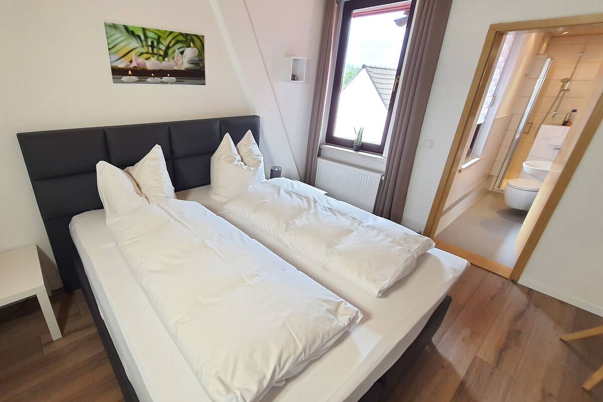 Une chambre à coucher avec un lit, une table de chevet et une fenêtre.