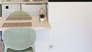 A modern kitchen with white cabinets, a tiled backsplash, a sink, and a countertop with a small plant. - Appartement Refait Avec Terrasse et vue Montagne (Saint-Denis)