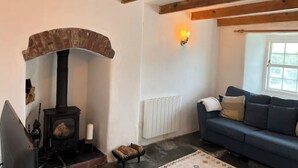 Een gezellige woonkamer met een open haard, een blauwe bank en een raam.