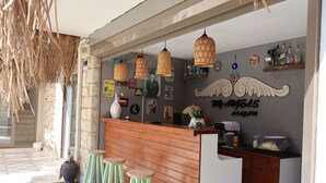 Un espace bar avec des tabourets en bois, des lampes en osier suspendues et différents éléments de décoration murale, notamment des tableaux encadrés et des panneaux.
