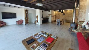 A spacious living area with a wooden ceiling, a large flat-screen TV, a dining table with chairs, and a red sofa. - Domaine de Codeval (Fronton)