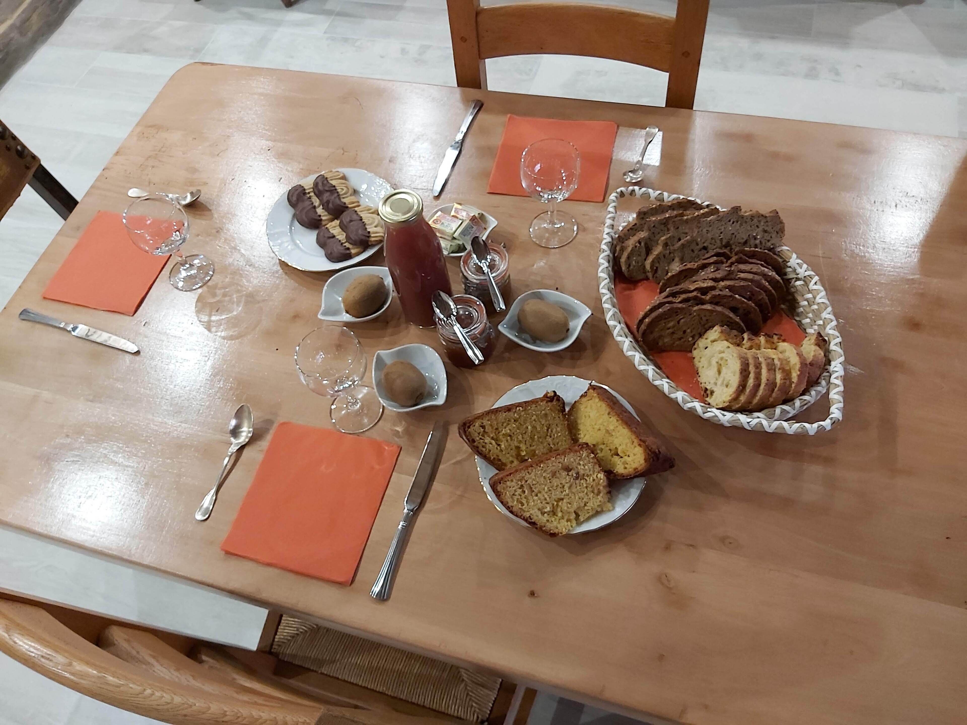 Ein Holztisch, reichhaltig mit Speisen gedeckt, darunter Brot, Kekse und eine Ketchupflasche.
