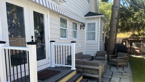 Een huis met een overdekte veranda, buiten zitplaatsen en een pad van stenen.