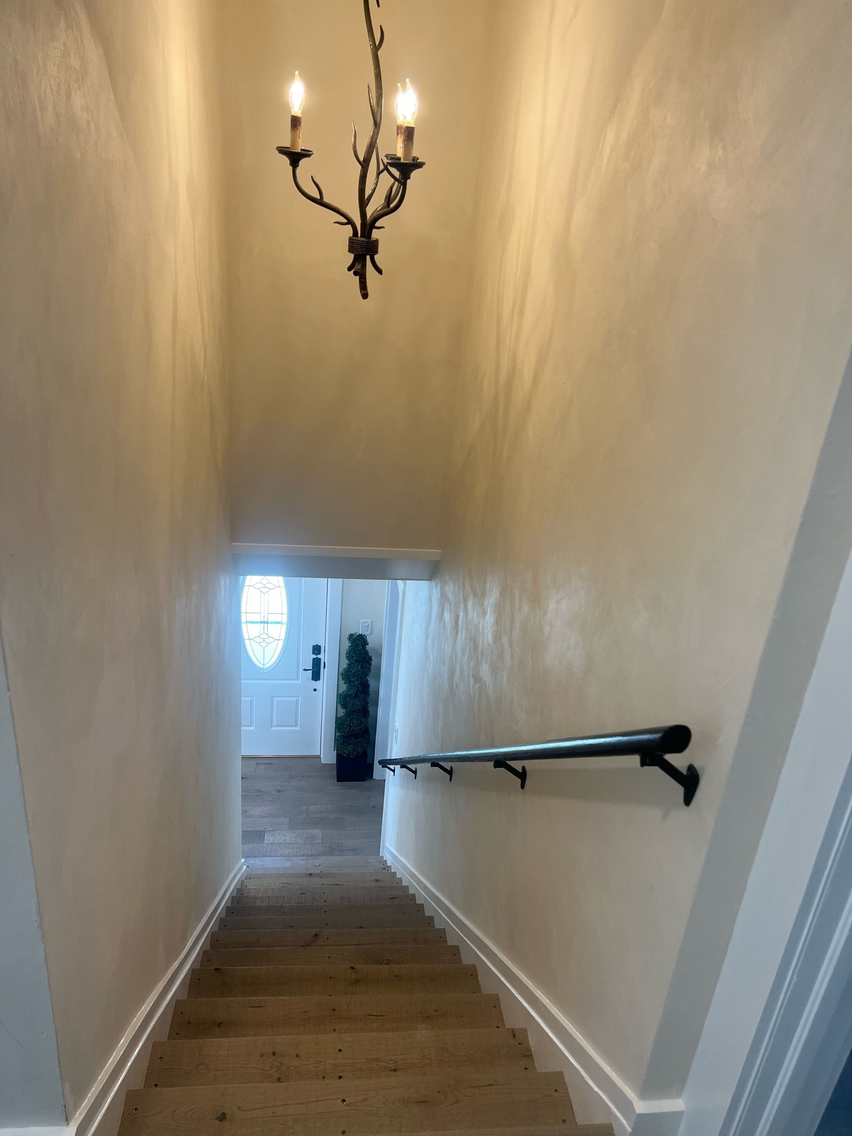 Una escalera de madera con barandilla que lleva a una puerta con ventanal.