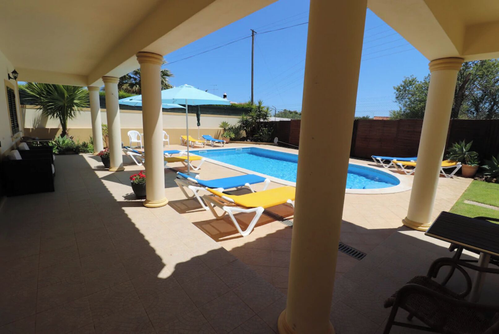 Un espace extérieur abrité comprenant une piscine, des chaises longues et une table de patio.